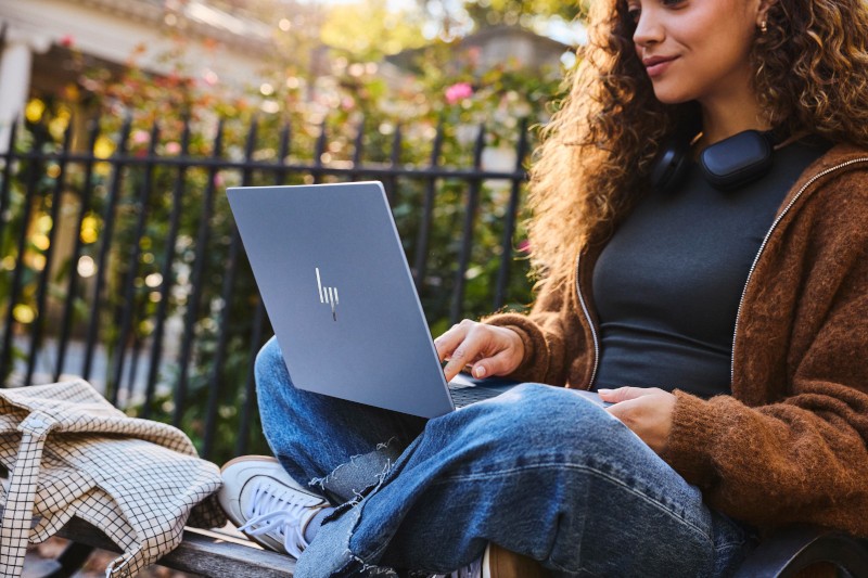 Kobieta pracuje na laptopie HP OmniBook 5 na ławce w parku